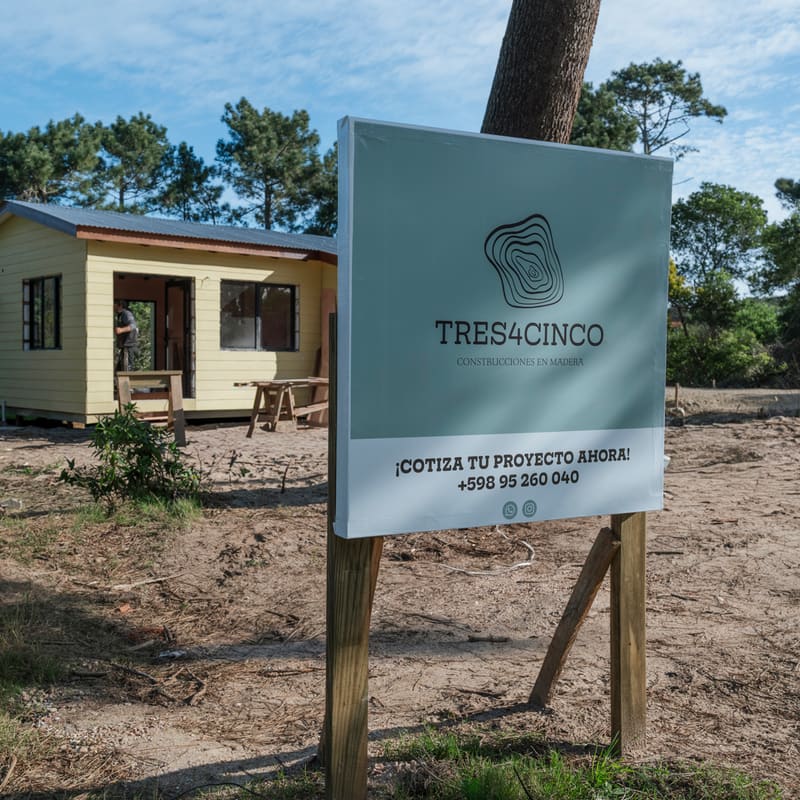 Finished yellow timber house behind a TRES4CINCO site sign.