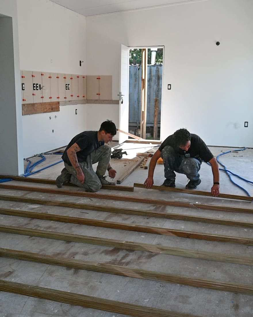 Two builders lay the battens for the floor inside.
