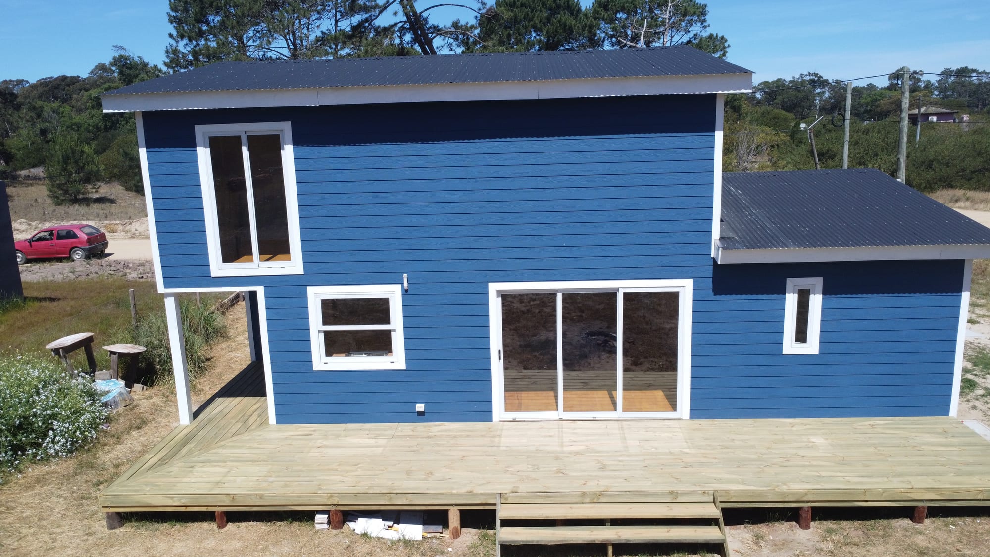 Rear of Casa Azul from the air: a large timber terrace with floor-to-ceiling sliding doors and blue facade.