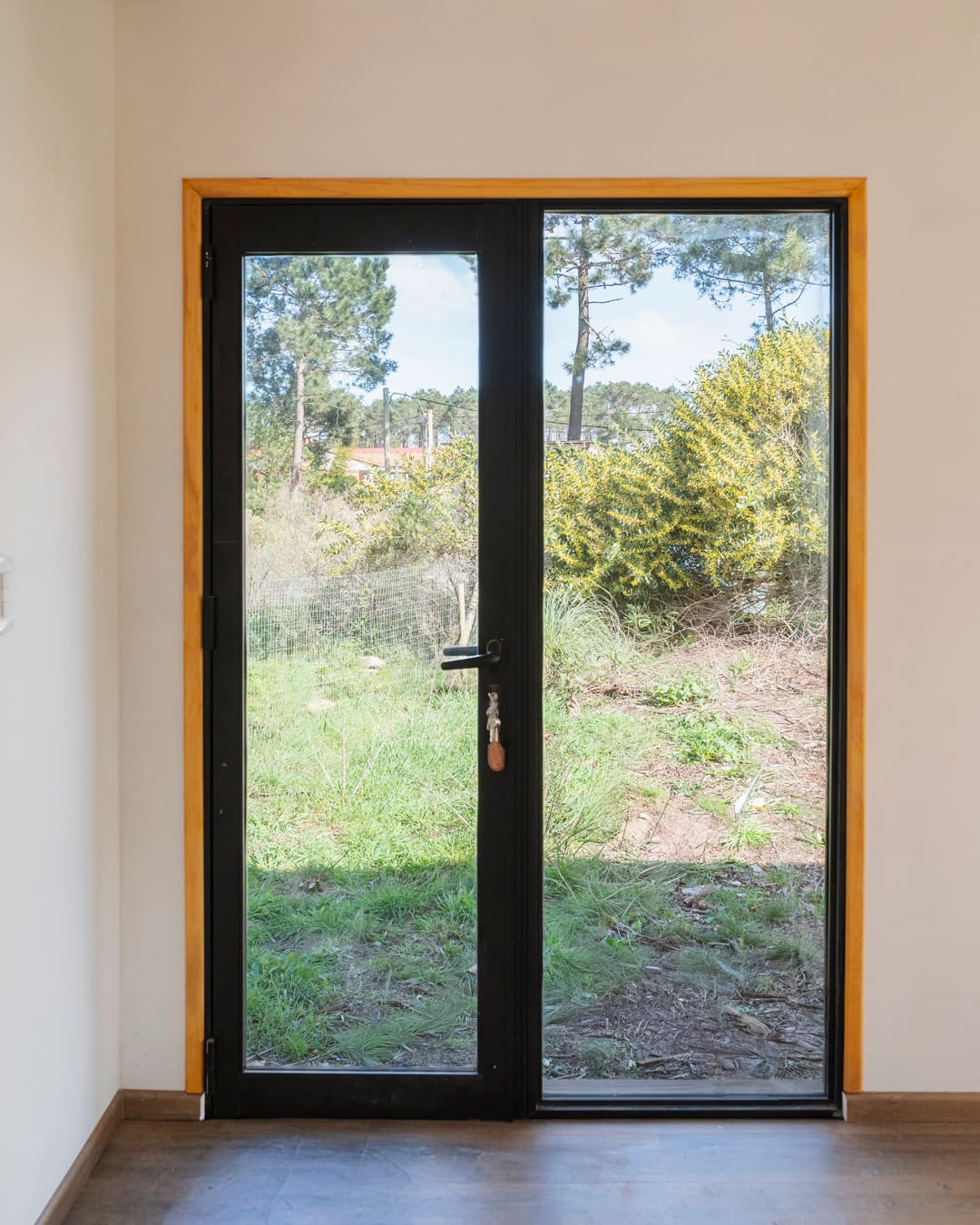 Glass door with a timber frame, the green garden behind.